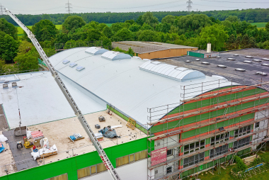 Blick über das Produktionsgebäude mit Flachdach und Tonnengewölbedach während der Sanierung