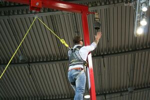  Mit verbundenen Augen, aber gesichert, balanciert ein Messebesucher auf einem Holzbalken in etwa drei Metern Höhe. Gesehen am Stand von Hammer Abbundtechnik 