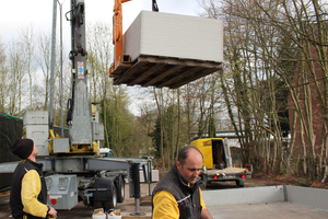 Ein Zimmermann hebt einen Stapel Gipskartonplatten per Kran vor den Rohbau 