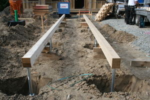  Zwei der Häuser stehen schon, hier werden die Leimholzunterzüge für ein drittes Haus platziert, bevor die Löcher mit Beton ausgegossen werden 