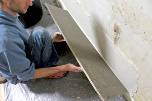  Nach dem Zuschnitt: die Holzfaserdämmplatte wird mit wenig Kleber an der Wand befestigt 