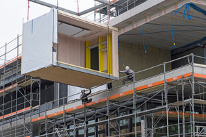  Ein Monteur der Renggli AG zieht eines der Holzmodule auf Schienen in das Nest-Gebäude 