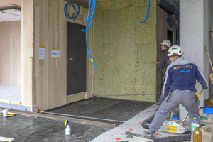  Ein Monteur der Renggli AG zieht eines der Holzmodule auf Schienen in das Forschungsgebäude Nest 