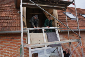  Gemeinsam heben Andreas Beermann (oben links), Harald Scheer (oben rechts) und zwei Fensterbauer das große Fenster für die Gaube ein<br /> 