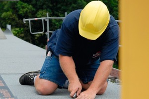  Ein Dachhandwerker schneidet aus der Dachfläche eine Gullyöffnung aus 