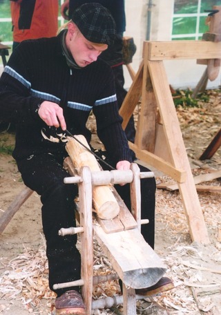 Arbeit mit dem Hobelpferd, dabei wird das Holz mit dem Ziehmesser geglaettet