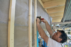  Ein Handwerker befestigt ein geerdetes Abschirmgewebe an den Holz-Außenwänden Foto: Institut für Baubiologie und Nachhaltigkeit  