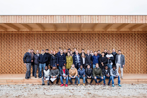  Das Bauteam aus Studenten der TU Kaiserslautern, Flüchtlingen, wissenschaftlichen Mitarbeitern und Professoren vor dem fertigen GemeinschaftshausFoto: Yannick Wegener, Mannheim 