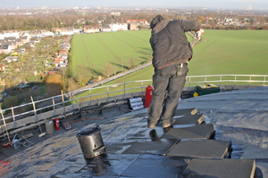  Ein Dachdecker trägt Heißbitumen auf Foamglas-Dämmplatten auf 