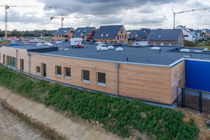  Außenansicht der Kita Korschenbroich von Norden mit Sicht auf die Holzfassade an der zukünftigen Hauptstraße des Baugebiets „An der Niers-Aue“ 