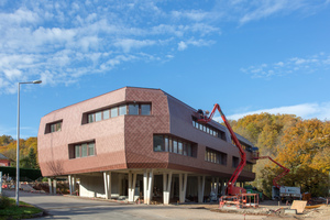  Der Neubau des Verwaltungsgebäudes ist mit einer Fassade aus Zinkschindeln versehen

 