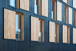  Schiebe-Fensterläden aus hellem Holz ergeben ein kontrastreiches Bild an der Fassade 