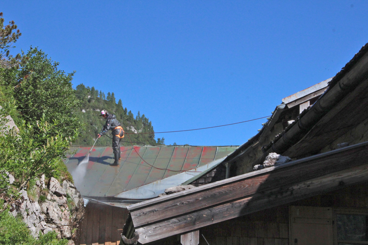 Dach mit einem Hochdruckgerät und ?SikaCor Wash? gereinigt. Der Handwerker ist mit Klettergurt und Seil gesichert Foto: Sika 