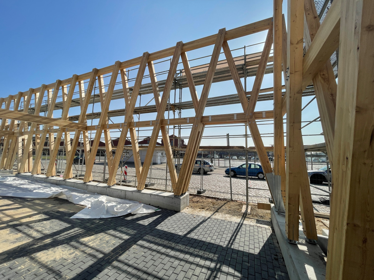 Das Tragwerk der Fassade wird aus zwei parallelen Reihen schräg gestellter Brettschichtholzstützen errichtet
