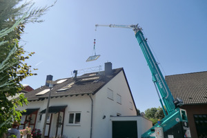  Absturzsicherung auf dem Steildach: Das Dachfenster wird per Kran eingehoben. Für den Einbau des Dachfensters haben die Dachdecker ein Leiter-Plattform-System für die Bauzeit montiert  