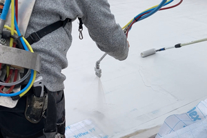  Anschließend wurde die maschinelle Flächenabdichtung mit „Triflex Protect“ durchgeführt. Während ein Maschinenführer die Abdichtung aufsprühte, legte ein anderer Handwerker das Spezialvlies ein 