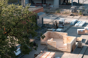  Der Pavillon aus „Triqbriq“-Holzbausteinen entsteht, im Hintergrund sind die Gebäude des ehemaligen Flughafens Berlin-Tegel zu sehen 