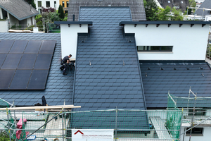  Anschlussarbeiten auf der Vorderseite des Daches. Links im Bild ist die Photovoltaikanlage zu sehen, die oberhalb der Aluminiumschindeln montiert wurde 