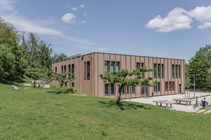  Eine Holzfassade mit vertikalen Lamellen und bodentiefen Fenstern prägt das äußere Erscheinungsbild des Neubaus 