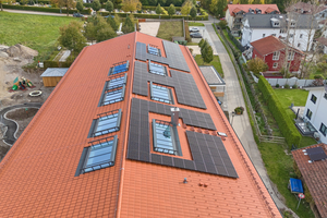  Auf dem flach geneigten Satteldach des Neubaus wurden neun Lichtbänder von Glasolux eingebaut. Auf der rechten Dachseite werden diese von Photovoltaikmodulen flankiert 