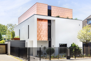  Der obere, kubenförmige Bereich der Villa in Köln-Rodenkirchen ist mit Kupferschindeln verkleidet. Der untere Bereich der Fassade ist in einem hellen Farbton verputzt 