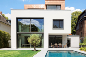  Zur Gartenseite hin zeigt sich der Neubau in Köln-Rodenkirchen offen, mit verglasten Fensterflächen und einer überdachten Terrasse 