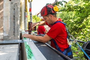  Die von Brüninghoff vorgefertigten Holzfassadenelemente werden vor Ort am Bestandsgebäude montiert 
