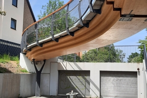  Mit ihrem geschwungenen Grundriss verläuft die Brücke von einer Freifläche des Quartiers am Frieslandring über die Zufahrt einer Tiefgarage und quert den Schwabenweg  