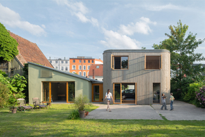 In Schwerin entstand in Hinterhoflage neben einer ehemaligen Autowerkstatt ein zweigeschossiges Einfamilienhaus. Die Baustoffe Holz, Stroh und Lehm spielten dabei eine große Rolle. Die teilweise gewölbten Außenwände wurden mit Douglasienholz verkleidet 