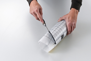  Dann wird das zweite Folienstück mit der glatten Seite nach außen um das Rohr gewickelt, mit einer Überlappung provisorisch auf der längeren Seite verklebt und entlang der schrägen Rohrkante abgeschnitten.  
