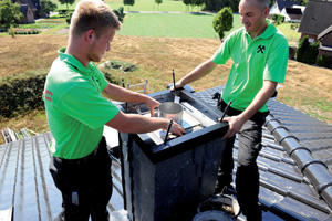  Der Schalungsrahmen wird auf den Kamin gesetzt. Im gleichen Zug setzen die Handwerker ein Dehnfugenblech ein, das den Beton daran hindert, in den Zug zu laufen. Gleichzeitig ziehen sie die Maueranker der Verkleidungen nach oben, so dass diese später fest im Beton verankert sind 