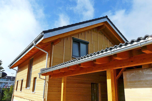  Ansicht des Neubaus zum Eingangsbereich mit offenem Carport und Abstellraum. Die Rhombus-Holzschalung ist zum Teil schon angebracht 