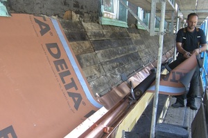  Dachrinne und Einhangblech aus Kupfer sind bereits verlegt. Es folgt die Vordeckung mit einer diffusionsoffenen Schalungsbahn. Danach können die Schiefer, Coquettes 20 x 40, die bereits auf dem Gerüst lagern, verlegt werden 