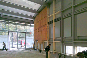  Montage der vorgefertigten Elemente auf der Holzunterkonstruktion. Im hinteren Teil des Stalls sind Unterkonstruktion und Installationen nicht mehr zu erkennen, deshalb konnte hier auf den grauen Anstrich verzichtet werden 