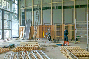  Die Leitungen der Gebäudetechnik und die Heizkörper sind installiert, die tragende Holzkonstruktion wurde hierfür mit Aussparungen versehen. Die horizontal montierten Holzriegel dienen zur Aufnahme der Horizontallasten aus dem Lastfall „Giraffenjuckreiz“ 