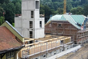  Rohbauphase: Der Erschließungsturm aus Stahlbeton steht, die ersten Holzrahmenelemente werden darum gruppier 


 