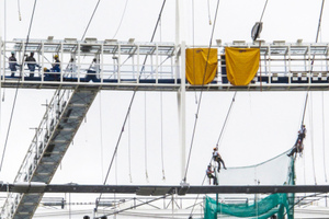  So genannte Alpine Workers bereiten das Seiltragwerk auf die Montage der Dachmembran vor. Links ein „Catwalk“, der vom Tribünenrand zum Wartungsgang führt 