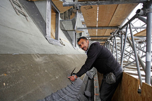  Ein Dachdecker bei der Abnahme eines Gebindes. Dabei wird die Unterkante eines Schiefergebindes auf der Lage darunter mit Kreide als Anhaltspunkt markiert


 