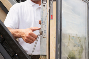  Als Vorbereitung für die Montage des Geländers fixiert der Handwerker den unteren Fensterflügel mit Montagestangen in senkrechter Position (wird später wieder entfernt) 
