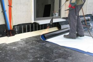  Das gedämmte Flachdach erhält die erste Abdichtungslage. Für eine optimale Verklebung am Rand wird die Bahn an den Enden kurz angeflammt 