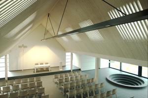  Die planebene Unterseite des Daches behält ihre schlichte, ruhige Erscheinung. Zugleich erzeugt das durch die Lamellenfelder einfallende Licht im Gottesdienstraum eine stimmungsvolle, sakrale Ästhetik 