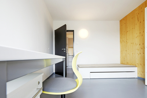  Wohnraum mit immer gleicher Ausstattung aus Bett, Schrank, Regal und Arbeitsplatz. Die Zimmerdecke ist weiß gestrichener Sichtbeton  Foto: LiWood / Sascha Kletzsch 