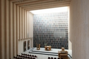  Das typische Gestaltungsprinzip des Büros Sauerbruch Hutton offenbart sich in der Kirche an der Stirnwand hinter dem Altar: ein aus unzähligen bunt gestrichenen Holzlamellen zusammengesetzter „Vorhang“, hinter dem sich die Orgel verbirgt 