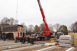  Der Kran hebt die Holzmodule auf das Beton-Streifenfundament
 