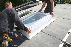  Der Aufsetzkranz des Flachdach-Fensters wird ohne Kuppel, aber noch mit der werkseitig angebrachten Schutzfolie, über der Dachöffnung positioniert und befestigt 
