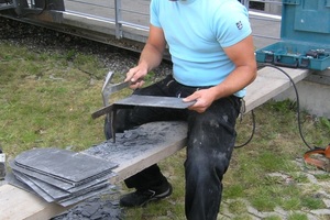  An der Baustelle werden die Strackortplatten vom Dachdecker mit Schieferhammer und Haubrücke zugerichtet 